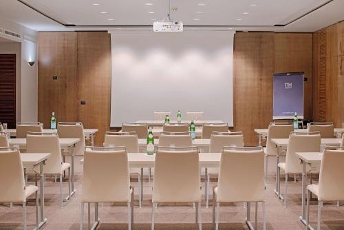 a room with tables and chairs and a projection screen at NH Napoli Panorama in Naples