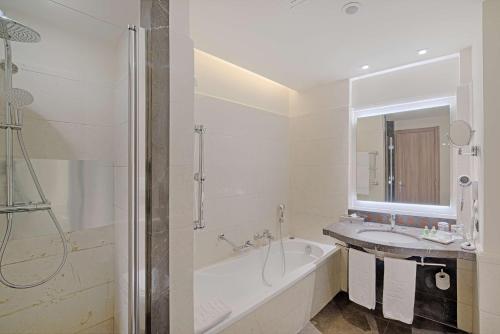 a bathroom with a tub and a sink and a mirror at NH Napoli Panorama in Naples