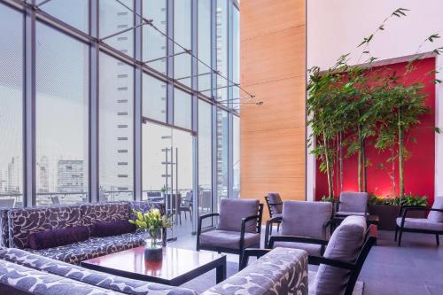 a restaurant with couches and tables and windows at NH Collection Mexico City Santa Fe in Mexico City
