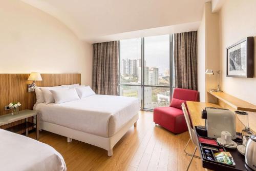a hotel room with a bed and a red chair at NH Collection Mexico City Santa Fe in Mexico City