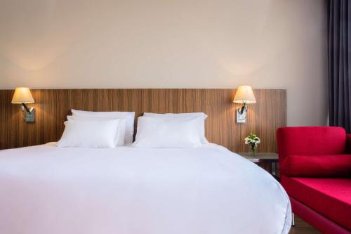 a bedroom with a large white bed and a red chair at NH Collection Mexico City Santa Fe in Mexico City