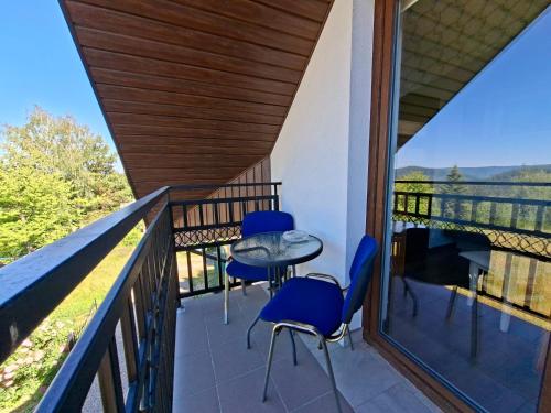 a balcony of a house with blue chairs and a table at Bieszczadzki Dom Gościnny w Werlasie in Werlas