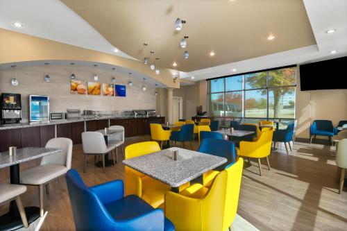 a restaurant with tables and yellow chairs at Comfort Suites Bentonville - Rogers in Bentonville