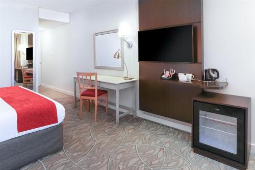 a hotel room with a bed and a desk and a television at Garden Court Nelson Mandela Boulevard in Cape Town