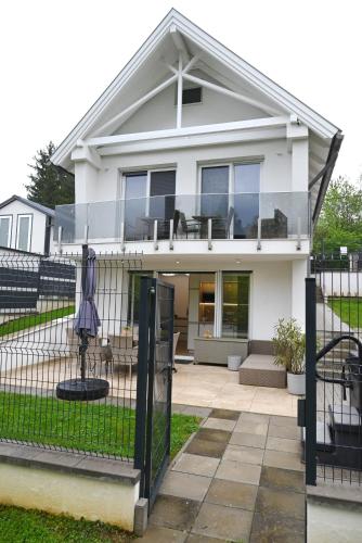 a white house with a fence and an umbrella at Tófény Őrségi Vendégház in Zalalövő