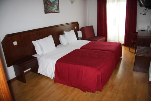 a bedroom with a large bed with a red blanket at Hotel Turismo Miranda in Miranda do Douro