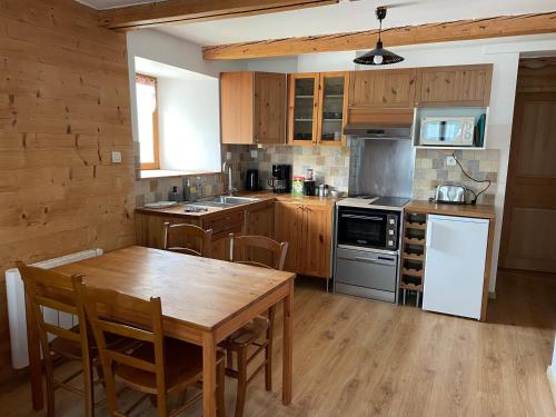 a kitchen with a wooden table and a wooden floor at Au cœur du massif jurassien in Les Rousses