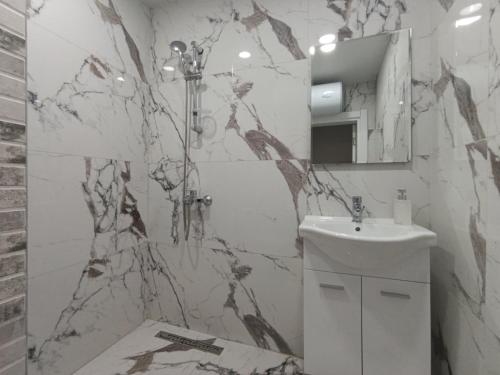 a bathroom with a white sink and a marble wall at Mareya Sky Residence Including Underground Parking Place in Sofia