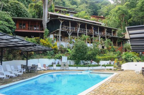 a hotel with a swimming pool in front of a building at Hostel Plinio in Manuel Antonio