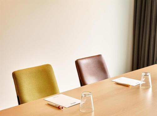 a table with two chairs and two glasses on it at Park Inn By Radisson Brussels Airport in Diegem