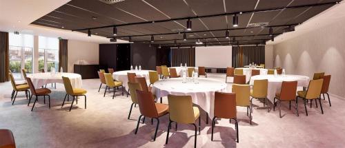 a room with white tables and chairs and a room with windows at Park Inn By Radisson Brussels Airport in Diegem