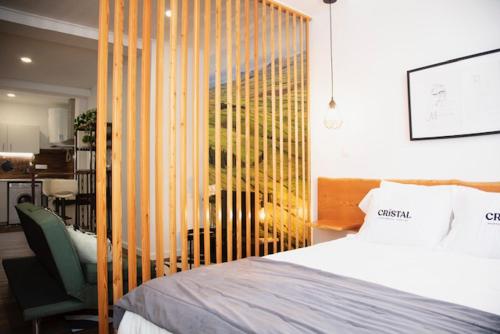 a bedroom with a bed and a chair and a window at Cristal apartamentos 1ºdireito Praça Velha in Angra do Heroísmo