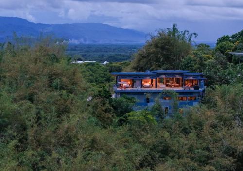 a blue house in the middle of a forest at Villa Buddha Belly OceanMountain top views in Quepos
