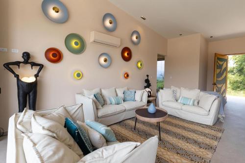 a living room with white couches and a wall with clocks at Villa Buddha Belly OceanMountain top views in Quepos