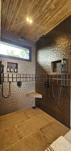 a bathroom with a shower in a stone wall at Villa Buddha Belly OceanMountain top views in Quepos
