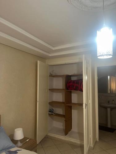 a room with a bed and a closet with shelves at Appartement proximité Gare TGV 3 in Kenitra