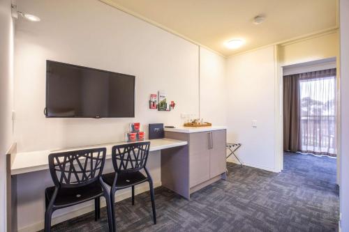 a room with two chairs and a desk with a flat screen tv at Nightcap at Shoppingtown Hotel in Doncaster
