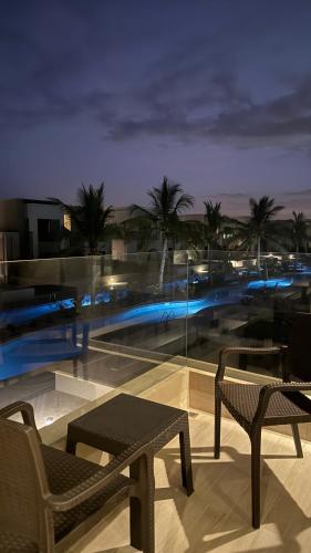 a balcony with two chairs and a view of a city at night at Dream Apartment - Near Beach with Pool View & WiFi in Salalah