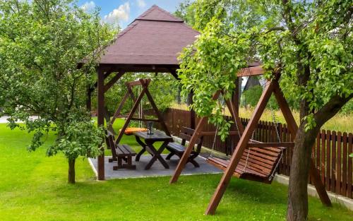 a wooden gazebo with a bench and a swing at Jurajska47 in Wola Kalinowska