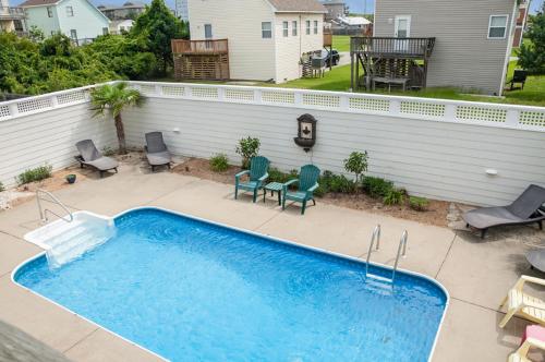 a swimming pool in a backyard with chairs and a table at Weekend at Pinchys in Kill Devil Hills