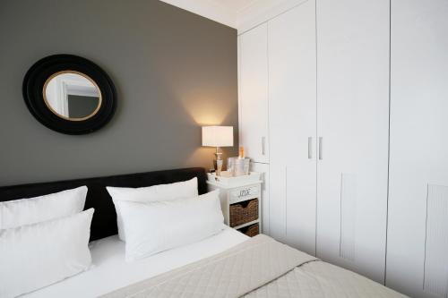 a bedroom with a bed with white pillows and a mirror at Das Windhuk in Westerland (Sylt)