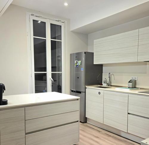 une cuisine avec des armoires blanches et un réfrigérateur en acier inoxydable dans l'établissement 3P Appart, 10' from Palais Festival Cannes, au Cannet