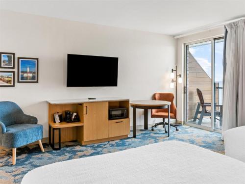 a hotel room with a television and a desk and chair at Hampton Inn St Ignace Lakefront Mackinac in Evergreen Shores
