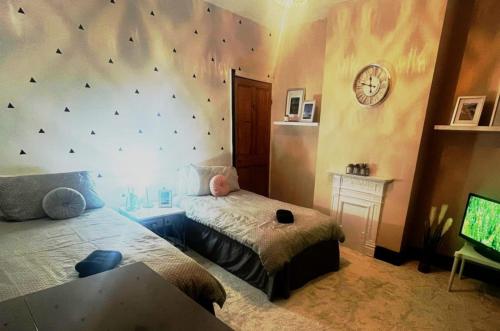 Un dormitorio con dos camas y un reloj en la pared. en Eton House, en Derby