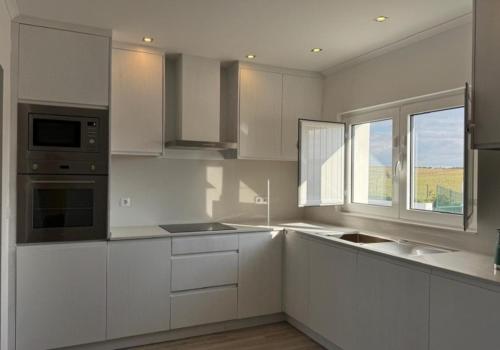 a white kitchen with white cabinets and a window at Monte Vale - Nature Resort in Entradas