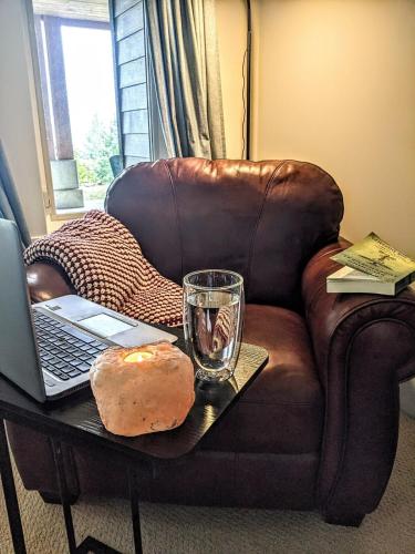 a coffee table with a laptop and a glass on a couch at Mountain House of Wonder in Qualicum Beach