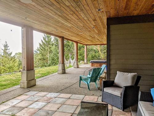 a porch with chairs and a wooden ceiling at Mountain House of Wonder in Qualicum Beach