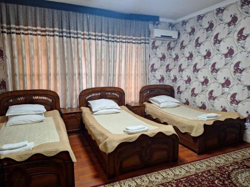 two twin beds in a room with a curtain at Shohruh Hotel in Guliston