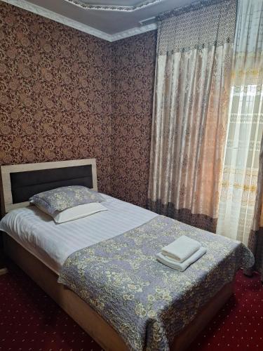a bedroom with a bed with two towels on it at Shohruh Hotel in Guliston