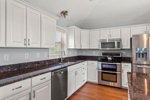 a kitchen with white cabinets and stainless steel appliances at Worthington Lane in Kitty Hawk