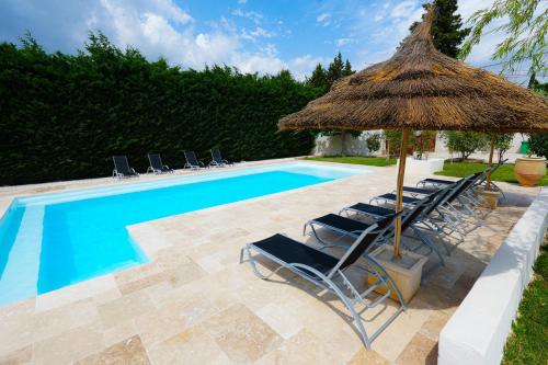 - un groupe de chaises et un parasol à côté de la piscine dans l'établissement Magnifique villa familiale avec piscine, à Caumont-sur-Durance