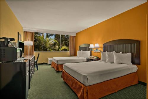 a hotel room with two beds and a television at Airport Honolulu Hotel, Trademark Collection by Wyndham in Honolulu
