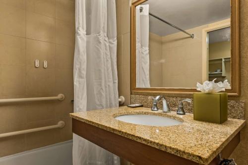 a bathroom with a sink and a mirror and a tub at Airport Honolulu Hotel, Trademark Collection by Wyndham in Honolulu