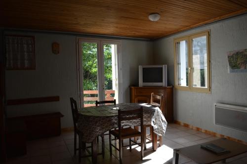 a dining room with a table and chairs and a television at logements les 4 fontaines in Gavarnie