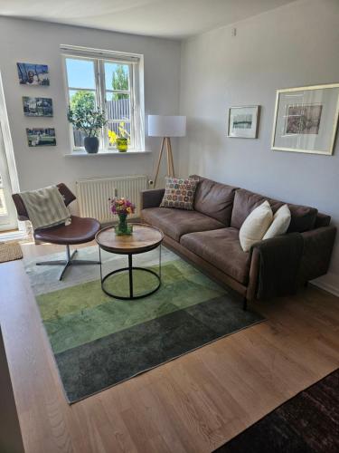 a living room with a brown couch and a table at Lejlighed B med dejlig privat gårdhave på Thurø Kæledyr er IKKE gratis og skal tilføjes in Svendborg