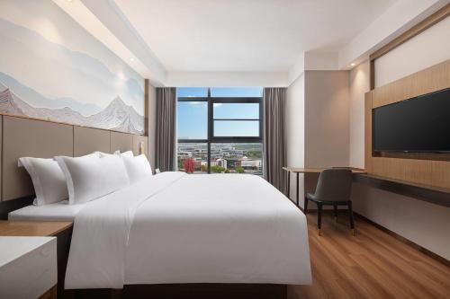 a hotel room with a large bed and a tv at Days Hotel by Wyndham Yancheng Hi-tech Park in Yancheng