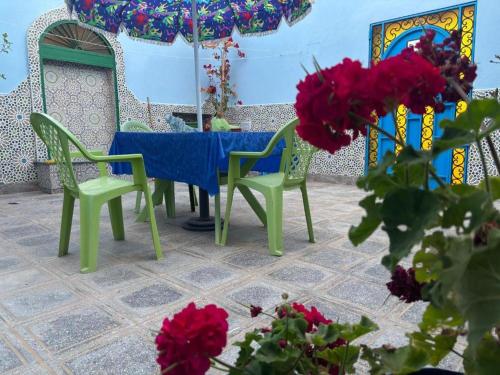 a table and chairs with a blue table and red flowers at Casa Morisca in Sidi Ifni