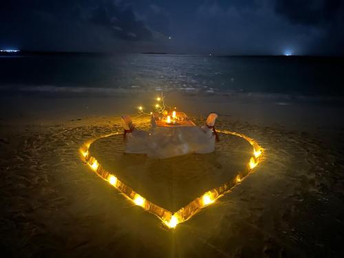 a heart shaped island with lights in the ocean at night at Handhuvaru Maldives in Milandu