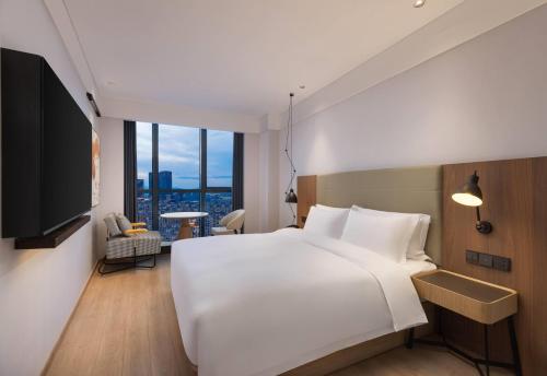 a bedroom with a large white bed and a large window at Ramada by Wyndham Hangzhou Yuhang in Hangzhou