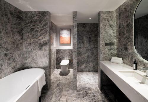 a bathroom with a tub and a sink and a mirror at Ramada by Wyndham Hangzhou Yuhang in Hangzhou