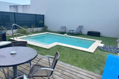a swimming pool in a yard with a table and chairs at Pleasant modern house t4 airco pool jacuzzi parking in Juvignac