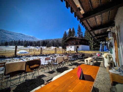 a goat standing on a porch with a table and chairs at Nattersbergalm in Reit im Winkl