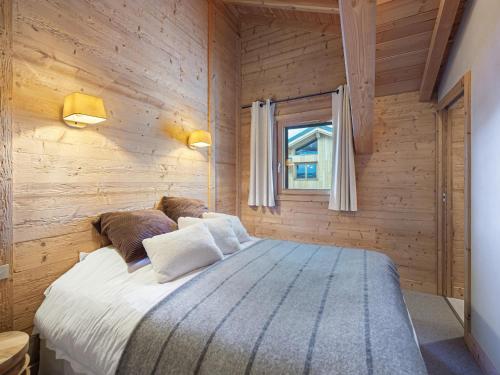 ein Schlafzimmer mit einem großen Bett an einer Holzwand in der Unterkunft Appartement neuf et cosy, proche des pistes, avec cheminée et parkings dédiés - FR-1-570-11 in Levassaix