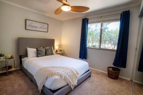 a bedroom with a bed and a window with blue curtains at Modern 2BR Mesa Condo in Central Location with Pool Access in Mesa