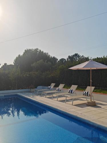 a group of lounge chairs and an umbrella next to a swimming pool at Montes da Salvada in Melides