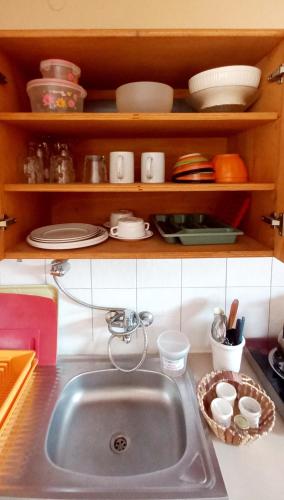 a kitchen sink with plates and dishes on a shelf at Busy Bee Apartments in Kololi